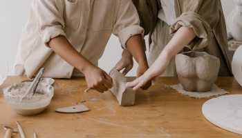 two sets of hands doing pottery together