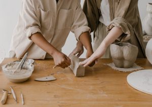 two sets of hands doing pottery together