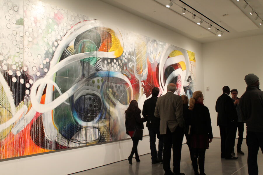 photo of people in a gallery next to a large abstract painting